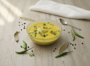 Traditional curry pakora kadhi served with rice, showing creamy yogurt curry with soft pakoras and spices